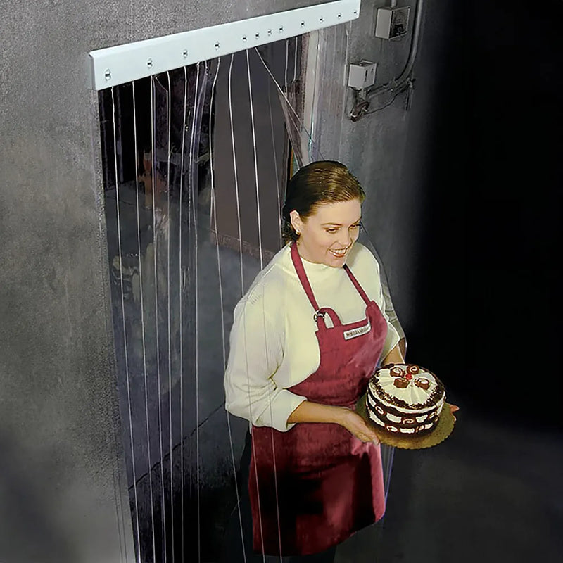 Curtron Curtronizer clear strip curtain door shown in use at a freezer doorway as a worker carries a cake through