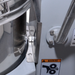 Alpha AVP-20 20 qt planetary stand mixer, close-up of the bowl arm clamp and gear warning label on the grey column