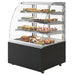 IGLOO DOMINIKA Series curved glass 3 tier refrigerated pastry display case with black base, stocked with desserts