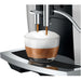 Jura E6 residential automatic coffee machine, close-up of the spout pouring a cappuccino onto the drip tray