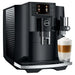 Jura E8 residential automatic coffee machine in piano black, angled view with a latte macchiato under the spout