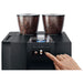 Jura GIGA X8 commercial automatic coffee machine, finger pressing the rear control button below the twin hoppers