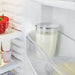 Jura glass milk container for automatic coffee machines, 16.7 oz, filled with milk and stored in a fridge door