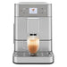 KitchenAid KES8556BK fully automatic espresso machine shown in stainless steel finish with a latte glass