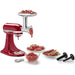 KitchenAid KSMMGA metal food grinder attachment on a red stand mixer grinding meat for sausages