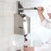 Nemco 10975 high volume bottle filler in use, chef pulling the lever to fill a squeeze bottle below the wall unit