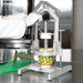 Nemco 55775 series Pineapple Corer/Peeler in use, gloved hand coring a pineapple on a green cutting board