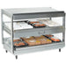 Nemco 6480 series heated pass through station, wider stainless steel model with slanted shelves stocked with hot food