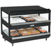 Nemco 6480 series heated pass through station, wider black model with slanted shelves stocked with packaged hot food