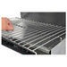 Omcan 39581 electric 18-inch adjustable salamander broiler, close-up of a hand lifting the chrome wire cooking grate