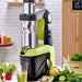 Omcan 45923 cold press juicer shown in use on a kitchen counter with fresh vegetables, fruit and green juice
