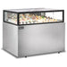 Omcan 48563 60-inch stainless steel flat top refrigerated pastry showcase stocked with cakes and desserts, angled view