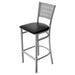 Tarrison Aria bar stool with silver metal frame, slotted back, footrest and black vinyl padded seat, angled view