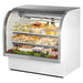 True TCGG-48-HC-LD 48-inch white curved glass refrigerated deli case with stainless trim, stocked with food