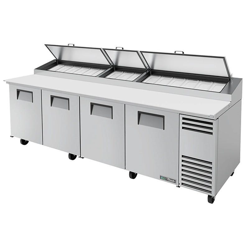 True TPP-AT-119-HC 119" four door stainless steel pizza prep table with lids raised and white cutting board