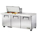 True TSSU-72-30M-B-ST-HC 72" three door stainless steel mega top sandwich prep table with lid open, angled left