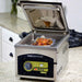 VacMaster VP215 chamber vacuum packaging machine in use on a kitchen counter, lid open with a sealed food pouch inside