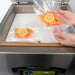 VacMaster VP320 chamber vacuum sealing machine in use, hands placing vacuum-sealed salmon pouches in the chamber