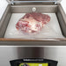 VacMaster VP320 chamber vacuum packaging machine, close-up of a vacuum-sealed cut of meat inside the chamber