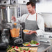 Vitamix 05201 XL blender in use as a chef adds ingredients to the large container in a commercial kitchen