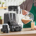 Vitamix 05202 XL programmable blender with smoothie being poured from the 64 oz container into a glass, in use