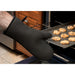Winco neoprene oven mitt shown in use, black mitt pulling a tray of baked cookies from a commercial oven