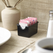 Winco black plastic sugar packet holder filled with sweetener packets on a cafe table setting, shown in use