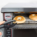 APW Wyott AT Express conveyor toaster shown in use with tongs loading bagel halves onto the conveyor