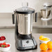 Hamilton Beach HBF1100SR Expeditor 4L blender and food processor on a kitchen counter beside fresh fruit