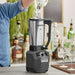 Hamilton Beach HBF510 Expeditor blender/food processor in use at a bar, pouring into the stainless steel container