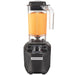 Hamilton Beach HBH455 Tango commercial blender in black with a 48 oz clear jar of orange smoothie, front view