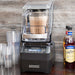 Hamilton Beach HBH755R Eclipse commercial blender on a bar counter with plastic cups and a bottle of syrup