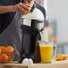 Hamilton Beach HCJ967 electric citrus juicer in use juicing oranges into a glass pitcher on a counter