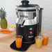 Hamilton Beach HJE960 commercial electric juicer on a counter with fresh carrots, pineapple and glasses of juice