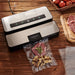 LEM 1393 MaxVac 250 out of chamber vacuum sealer in use, sealing a bag of steak on a wooden kitchen table