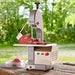 LEM 1561 table top meat saw shown outdoors cutting a large piece of beef on the saw's sliding cutting table