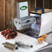 LEM 602TJ Big Bite 2 in 1 slicer and tenderizer on a grinder with sliced jerky strips and a spare roller