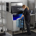 Nordic Air NIM-500C cube ice machine in use in a commercial kitchen, staff member filling a container from the bin