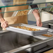 Phoenix STP24 series anti-jam steam table pan in use, shallow pan of food lowered into a buffet steam table