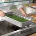 Phoenix STP24 series anti-jam steam table pan in use, pan of green beans placed into a steam table well