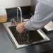 Phoenix stainless steel drop in sink shown in use, installed in a countertop while hands are washed
