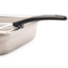 Winco one-piece portion controller with black handle hooked on the edge of a stainless steel food pan